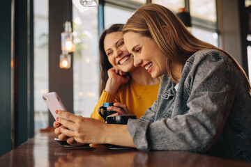 Friends at cafe using phone and smiling