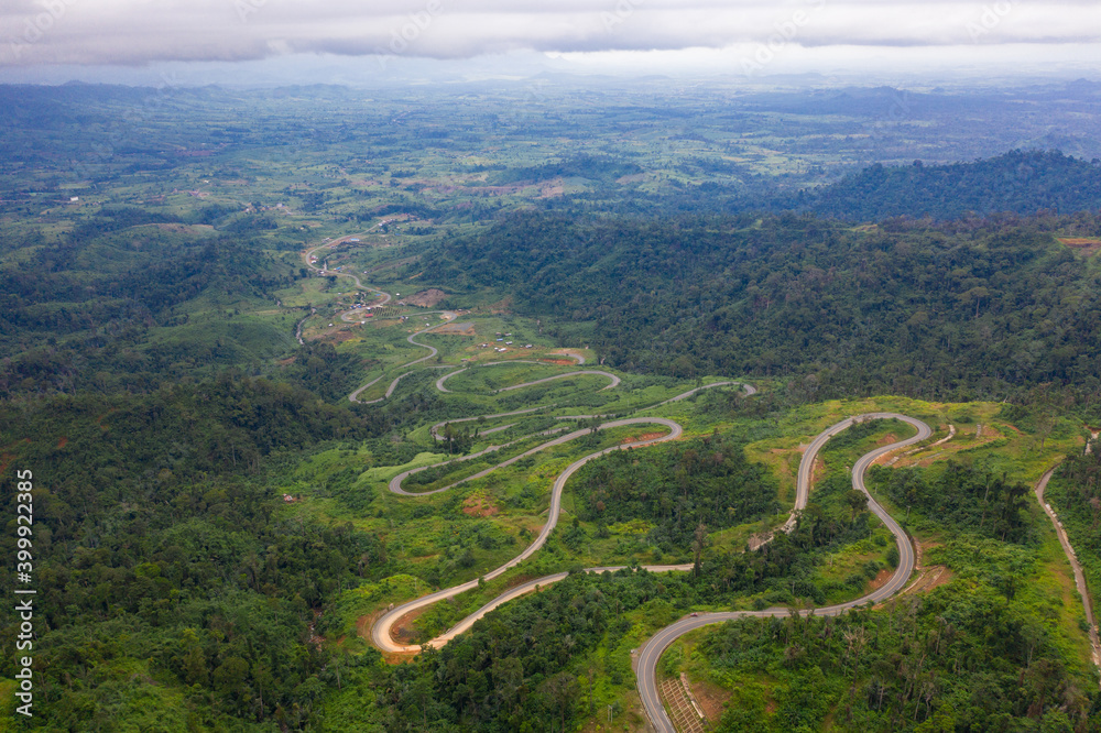 Winding road from the high mountain pass in Cambodia - Thailand Great road trip trough the dense woods. Aerial view.