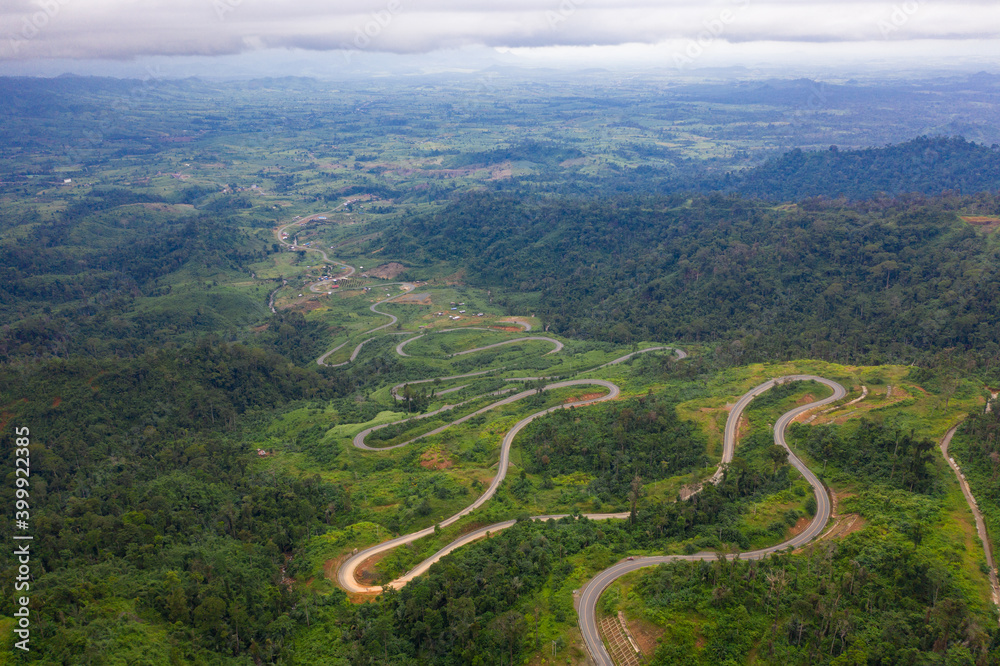 Winding road from the high mountain pass in Cambodia - Thailand Great road trip trough the dense woods. Aerial view. Winding road from the high mountain pass in Cambodia - Thailand Great road trip trough the dense woods. Aerial view.