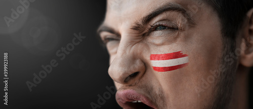 A screaming man with the image of the country's national flag on his face photo