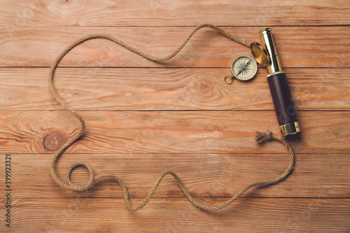 Frame made of rope, spyglass and vintage compass on wooden background