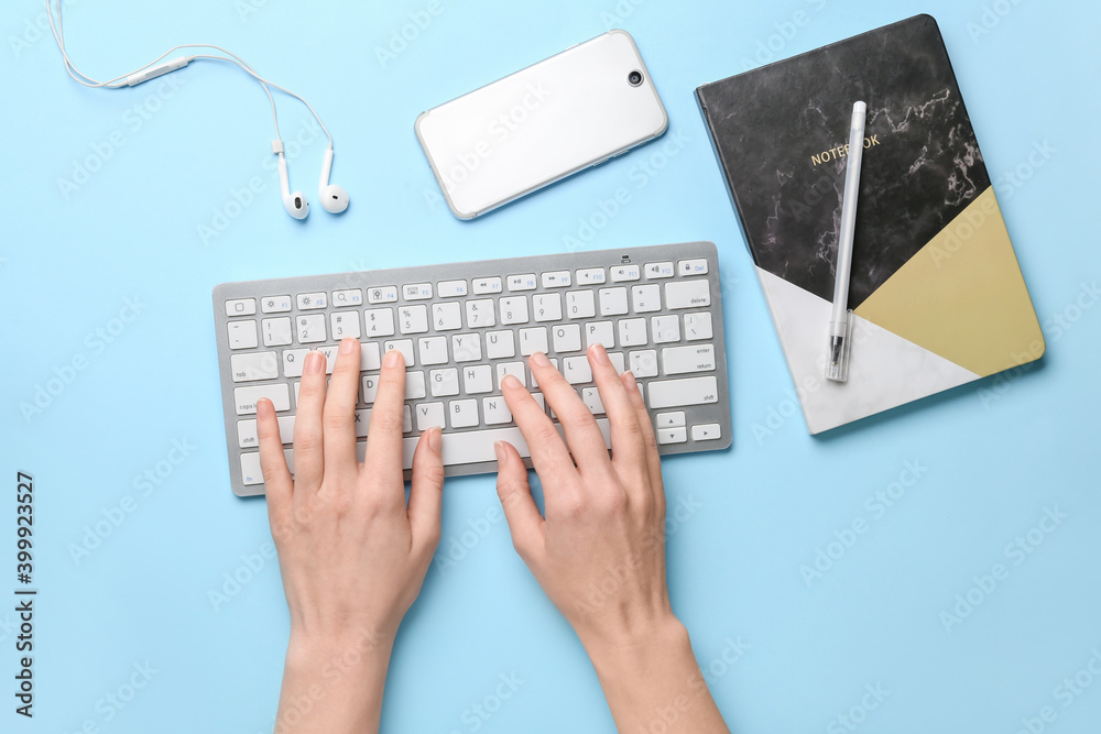 Female hands with computer keyboard, gadgets and stationery on color background Female hands with computer keyboard, gadgets and stationery on color background