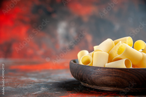 Half shot of uncooked pastas in a brown bowl on a dark background photo