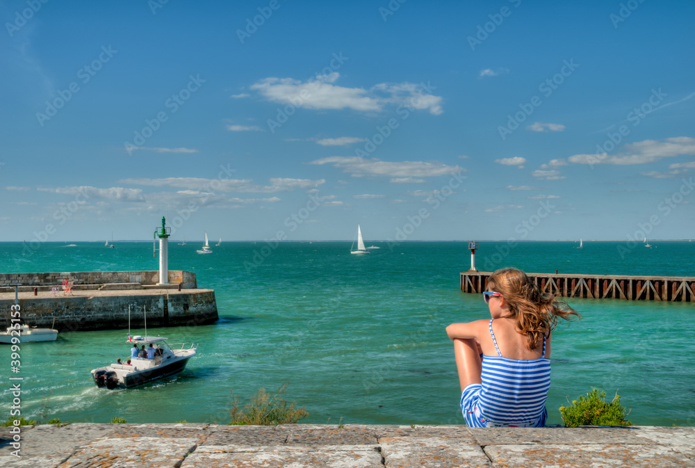 vu sur l'entré d'un port de pêche sur une ile de France avec fille de dos en marinière bleu sur une mère turquoise en France 