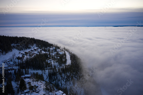 Fototapeta Naklejka Na Ścianę i Meble -  Arial: Photo shot with a drone. Fog in the valley below.  Norway, Oslo, Holmenkollen.