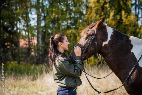Cute girl talking with her horse after a joint walk in the background of the forest. © Anna Kosolapova