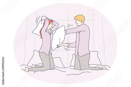 Pillow fighting and battle concept. Young happy couple fighting with pillows in bed and having fun during funny cheerful jaunt pastime together at home 