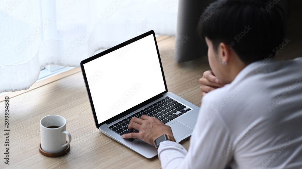 Rear view of young man freelancer lying on wooden floor in living room and using computer laptop. Rear view of young man freelancer lying on wooden floor in living room and using computer laptop.