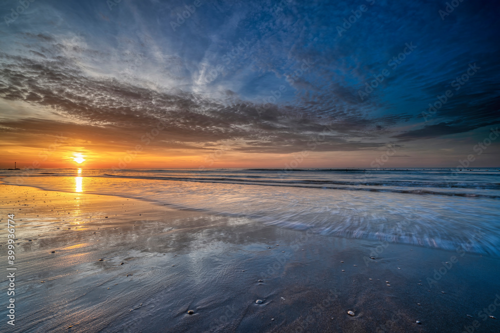Beautiful sunset on the beach. Seascape at the sunrise. An impressive blue and golden sky
