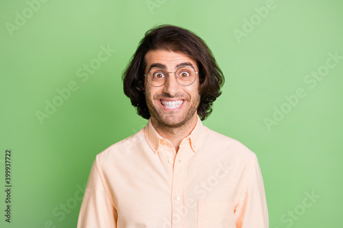 Portrait of attractive funky childish cheerful guy nerd geek wearing specs isolated over bright green color background © deagreez