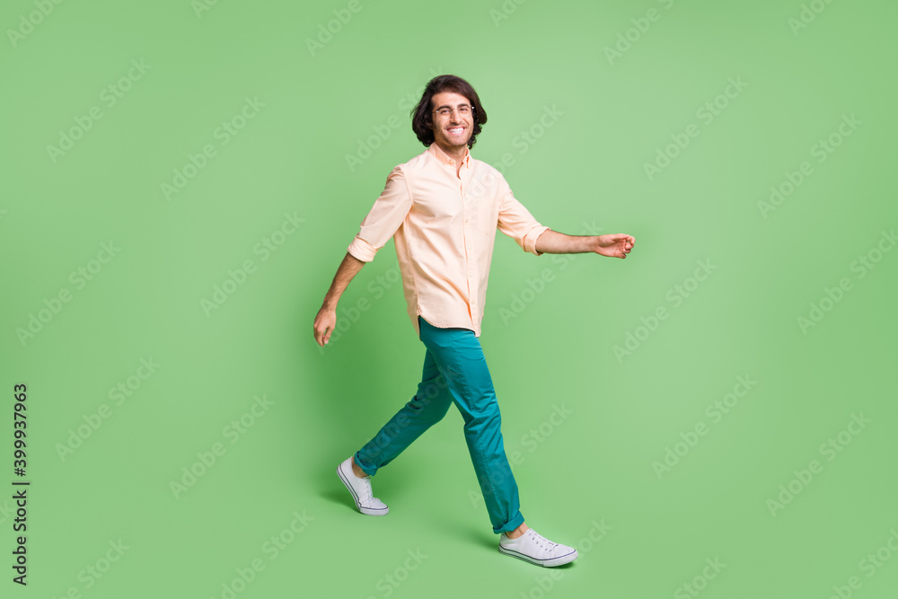 Full length body size profile side view of attractiv cheery guy wearing casual clothes going isolated over bright green color background Full length body size profile side view of attractiv cheery guy wearing casual clothes going isolated over bright green color background