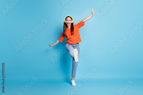 Photo of cheerful woman wearing casual red t-shirt dancing one leg listening favorite song isolated blue color background