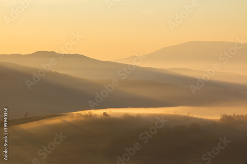 Landscape of mountains at sunrise in the fog. Beautiful background.
