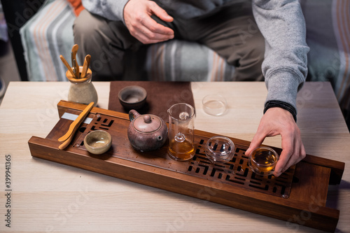 An oriental master conducts a tea ceremony for a visitor to a tea shop. Close-up with a tea set and a bamboo tray photo