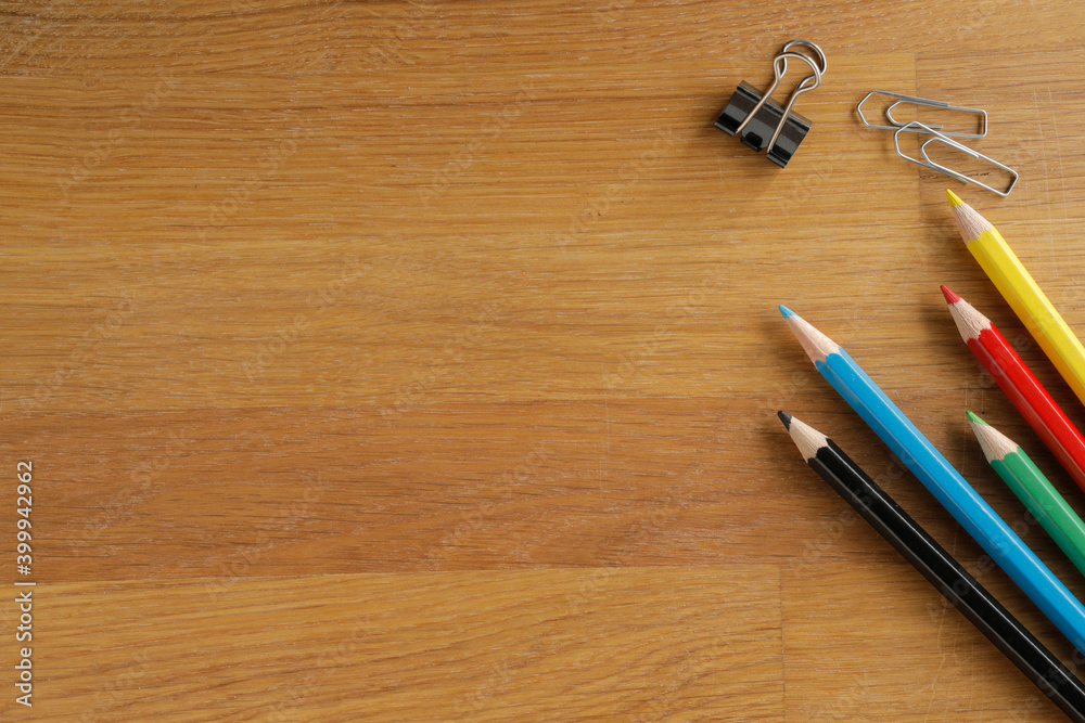 Distance learning, on a wooden table lay multi colored pencils and clips down, table top view with space for text Distance learning, on a wooden table lay multi colored pencils and clips down, table top view with space for text