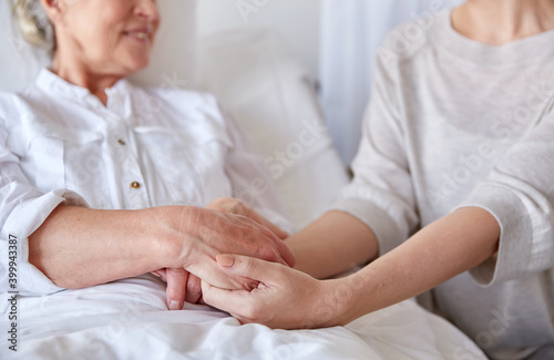 medicine  support  family health care and people concept - adult daughter visiting senior woman and cheering her at hospital