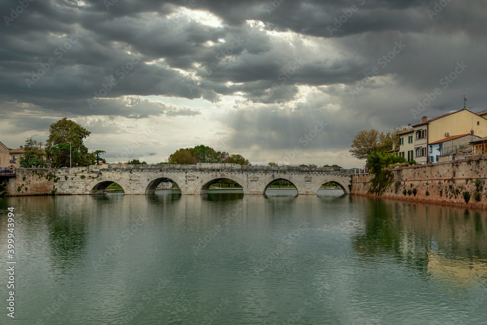 The ancient Tiberius Bridge in Rimini, Italy, under a dramatic sky