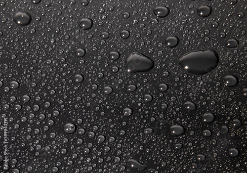 Condensation water drops on black glass background. Rain droplets with on dark surface. Abstract wet texture.