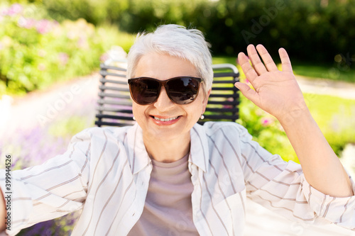 technology, old age and people concept - happy smiling senior woman in sunglasses taking selfie or having video call at summer garden