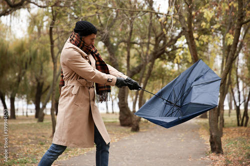 Man with blue umbrella caught in gust of wind outdoors photo