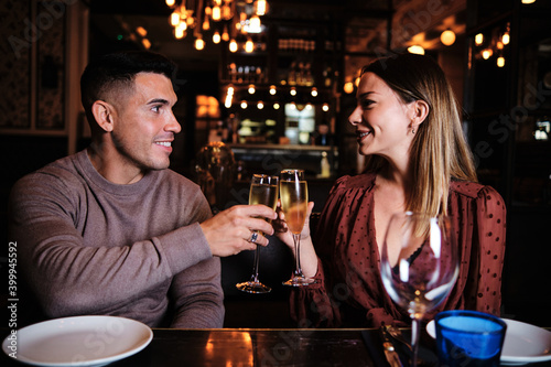 Couple having a date and toasting at restaurant.