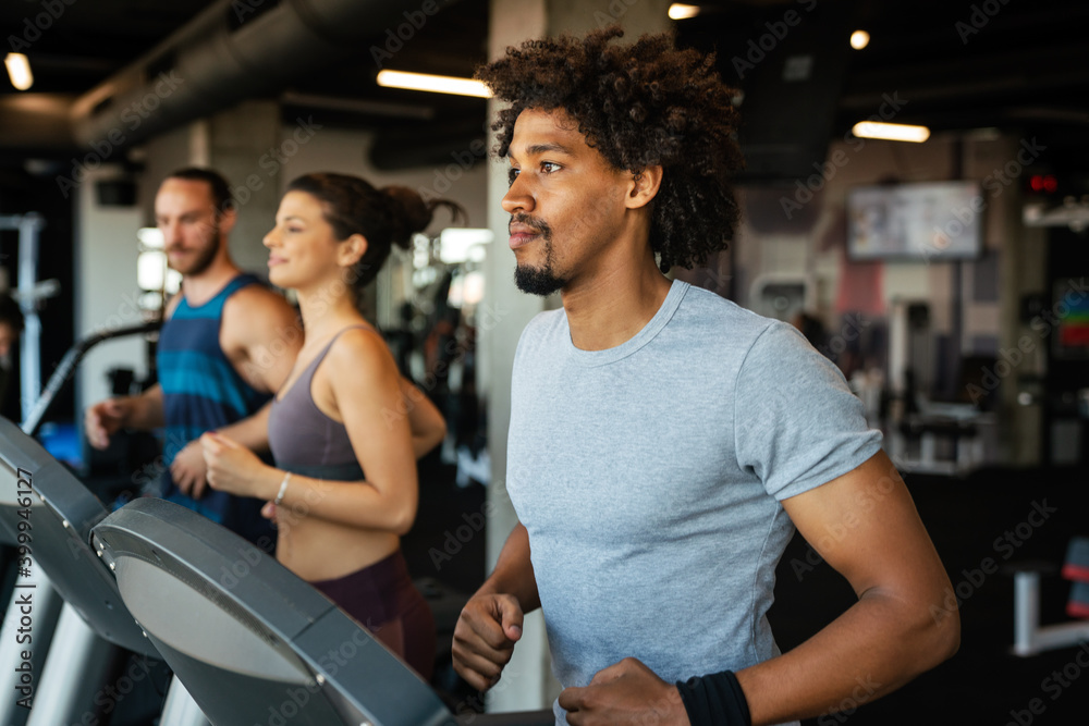 Group of young people running on treadmills in sport gym