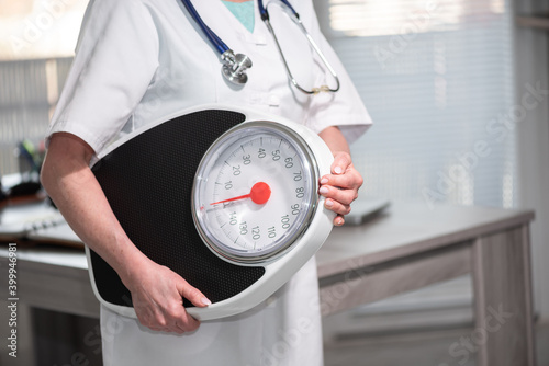 Female doctor holding a weight scale