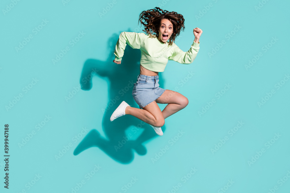 Full length body size photo of crazy energetic active girl jumping high fooling shouting isolated on vibrant teal color background