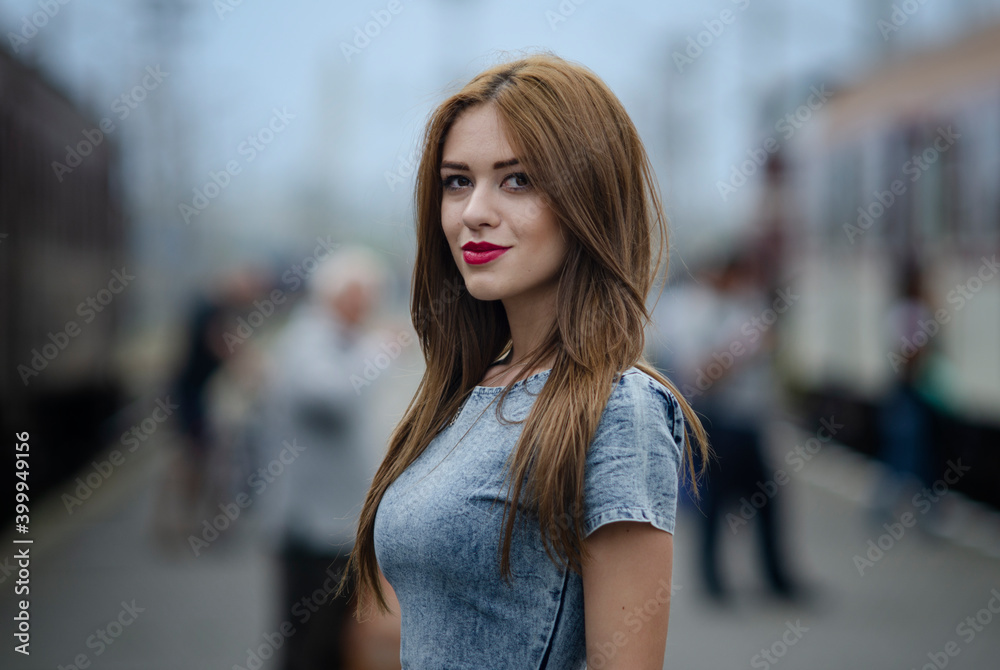 Fototapeta premium Beautiful young brunette woman with blue dress on a street urban background