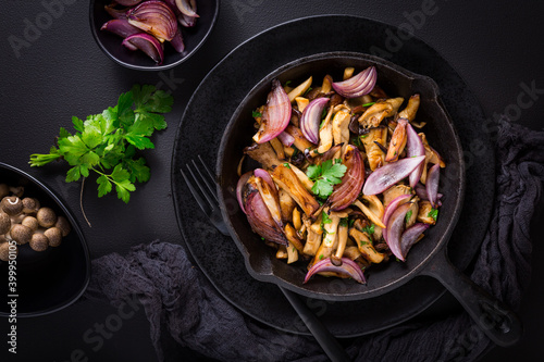 Fried mushrooms with onions and herbs on dark background photo