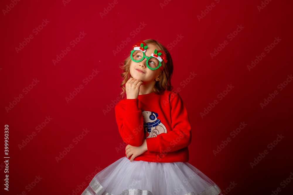 little girl in carnival glasses holds a gift on a red background, christmas