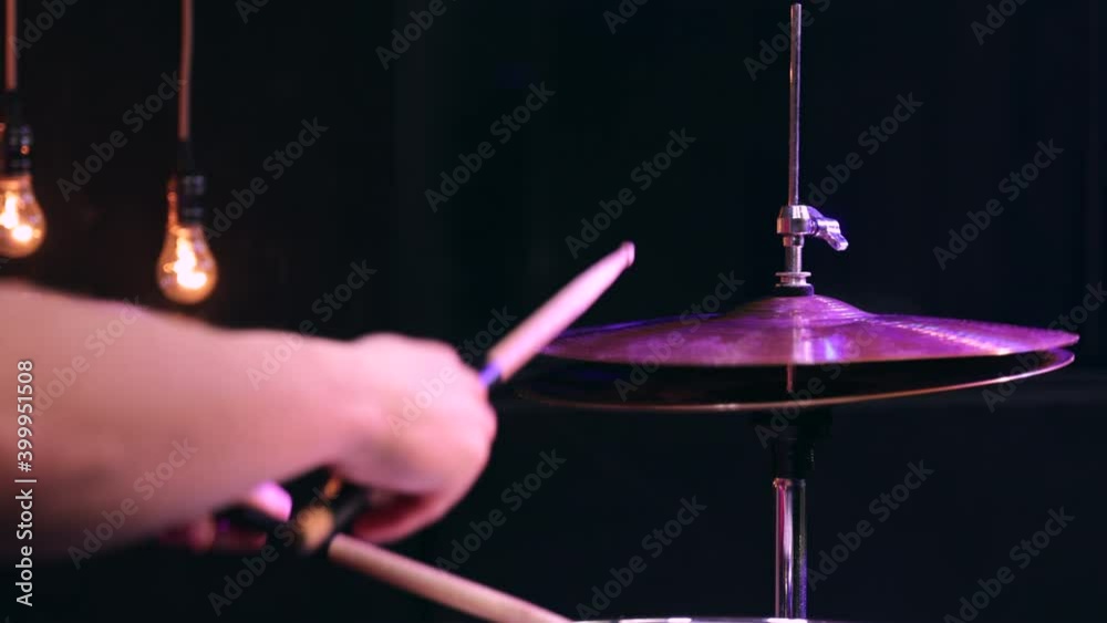 Man playing on snare and hi-hat with drumsticks. Closeup.