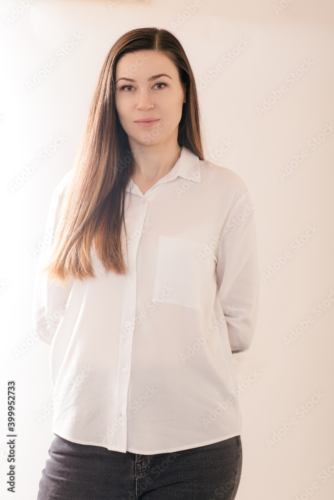Brunnette woman in a white shirt hides her hands behind her back Brunnette woman in a white shirt hides her hands behind her back