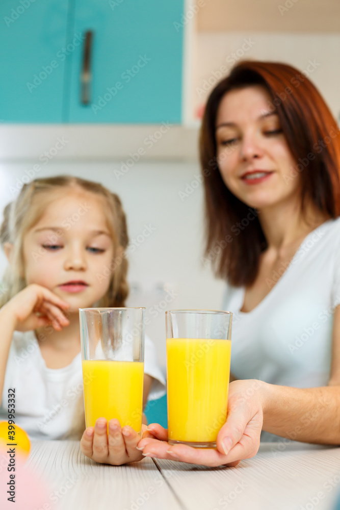 Mother with little girl drinking orange juice while they have breakfast together Mother with little girl drinking orange juice while they have breakfast together