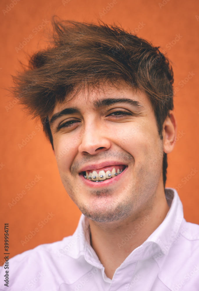 Fototapeta premium Guy in white shirt smiling on an orange wall.