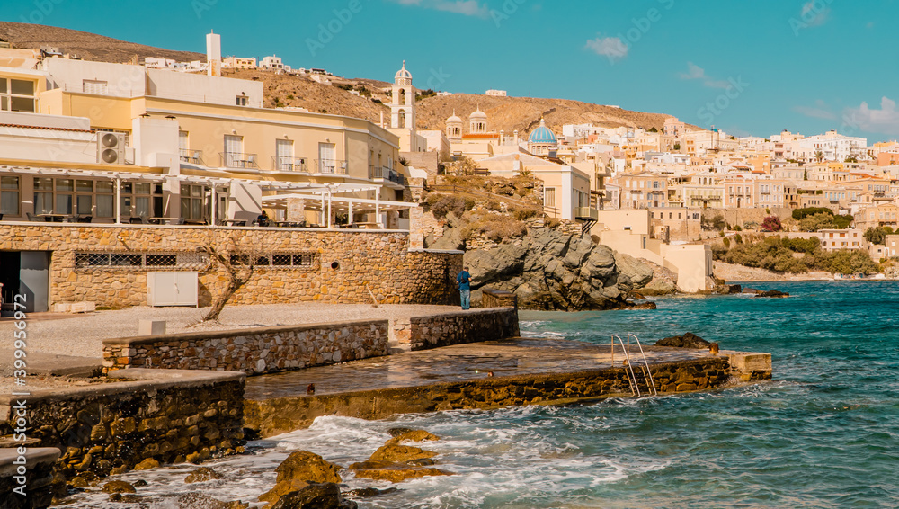 Stone beach in Ermoupolis on the islands of Syros, Cyclades, Greece with panorama view of the town in background