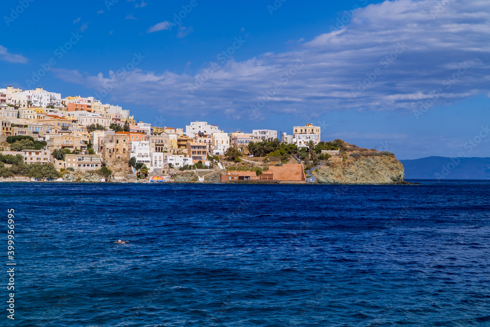 Swimmer in the Aegean Sea near the city beach in Ermoupolis on the islands of Syros, Cyclades, Greece with panorama of Ermoupoli town in the background