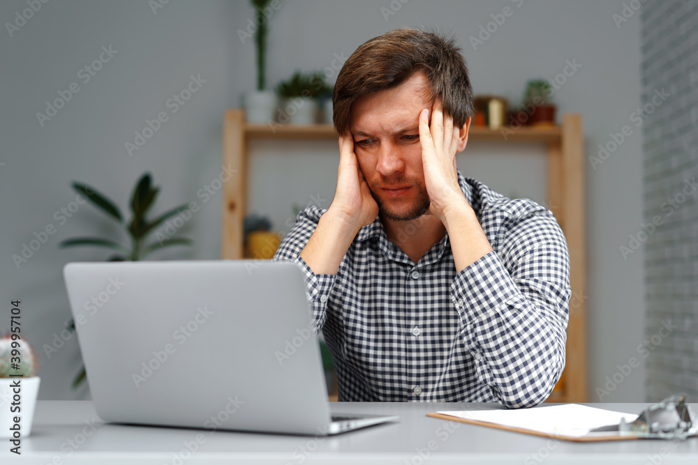 Young man working on laptop at his working table Young man working on laptop at his working table