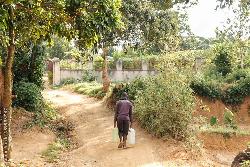 Man carrying water cans in Uganda, Africa