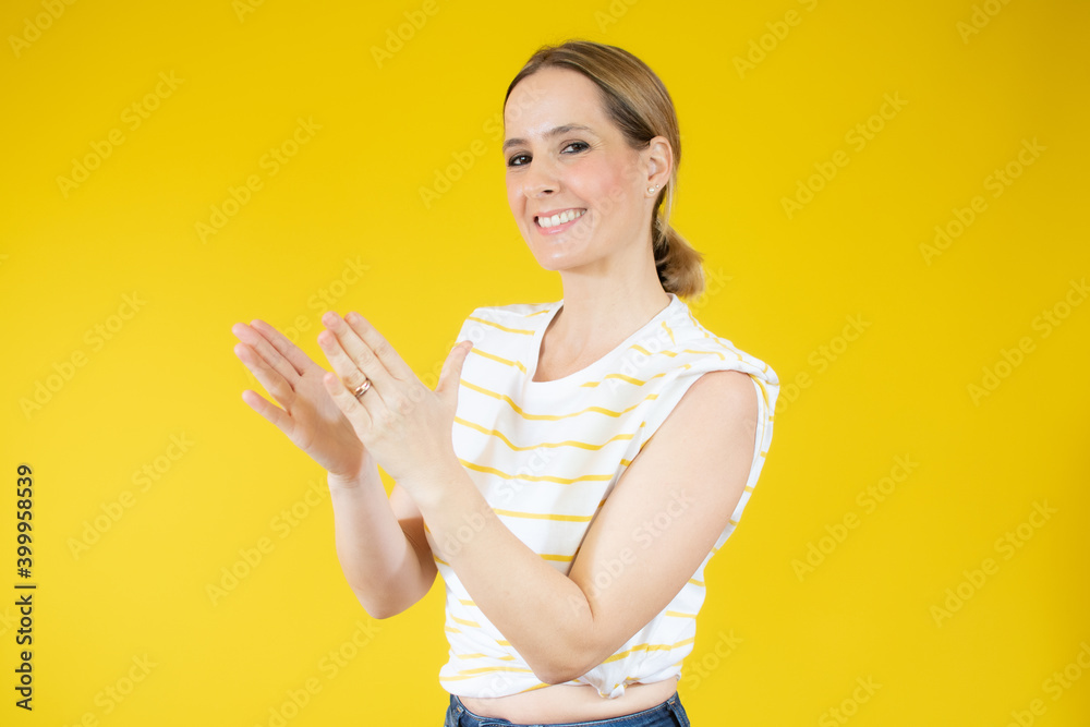 young pretty woman feeling happy and successful, smiling and clapping hands, saying congratulations with an applause against yellow background. young pretty woman feeling happy and successful, smiling and clapping hands, saying congratulations with an applause against yellow background.