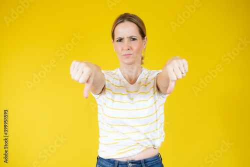 Portrait of displeased woman in casual t-shirt showing thumbs down