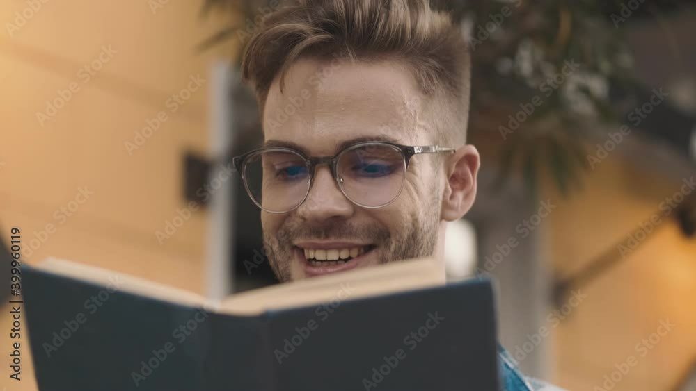 Smiling young man reading a book outdoors on the street Smiling young man reading a book outdoors on the street