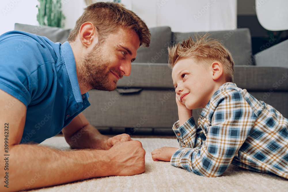 Father and son playing together on carpet at home Father and son playing together on carpet at home