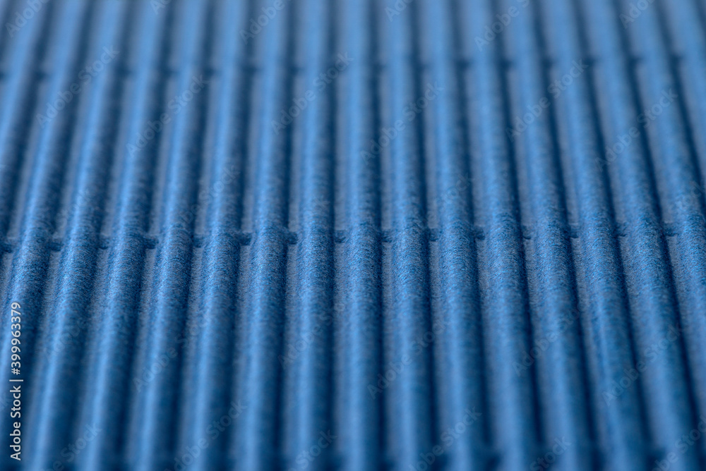 Background made of blue corrugated cardboard with vertical stripes, shallow depth of field.