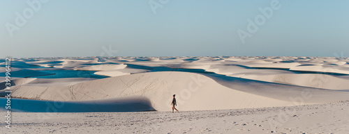 Solo female backpacker walks across the sand dunes of Lencois Maranhenses, miles and miles of sand dunes and lagoons in Maranhao, North-Eastern Brazil photo