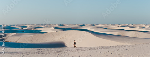 Solo female backpacker walks across the sand dunes of Lencois Maranhenses, miles and miles of sand dunes and lagoons in Maranhao, North-Eastern Brazil