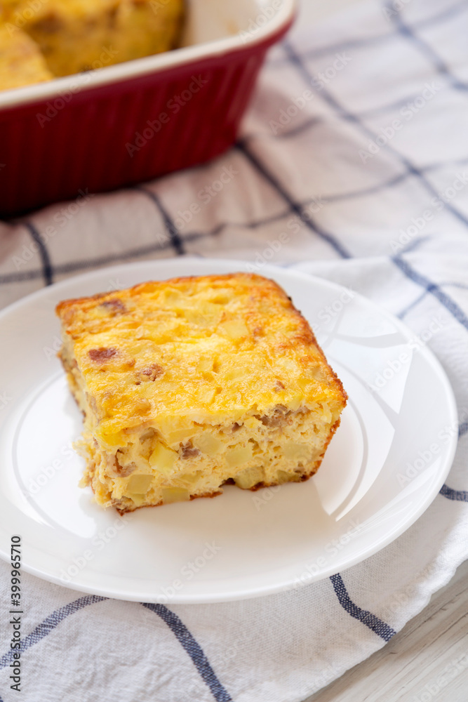 Homemade Cheesy Amish Breakfast Casserole on a white wooden surface, side view.