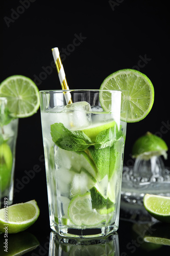 Delicious mojito and ingredients on black background