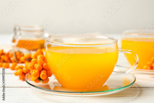 Delicious sea buckthorn tea and fresh berries on white wooden table