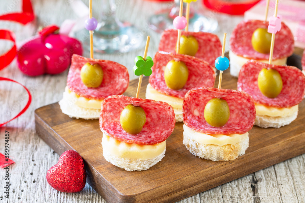 Valentines day or birthday romantic snacks close-up. Canapes with bread, cheese, salami and olives.